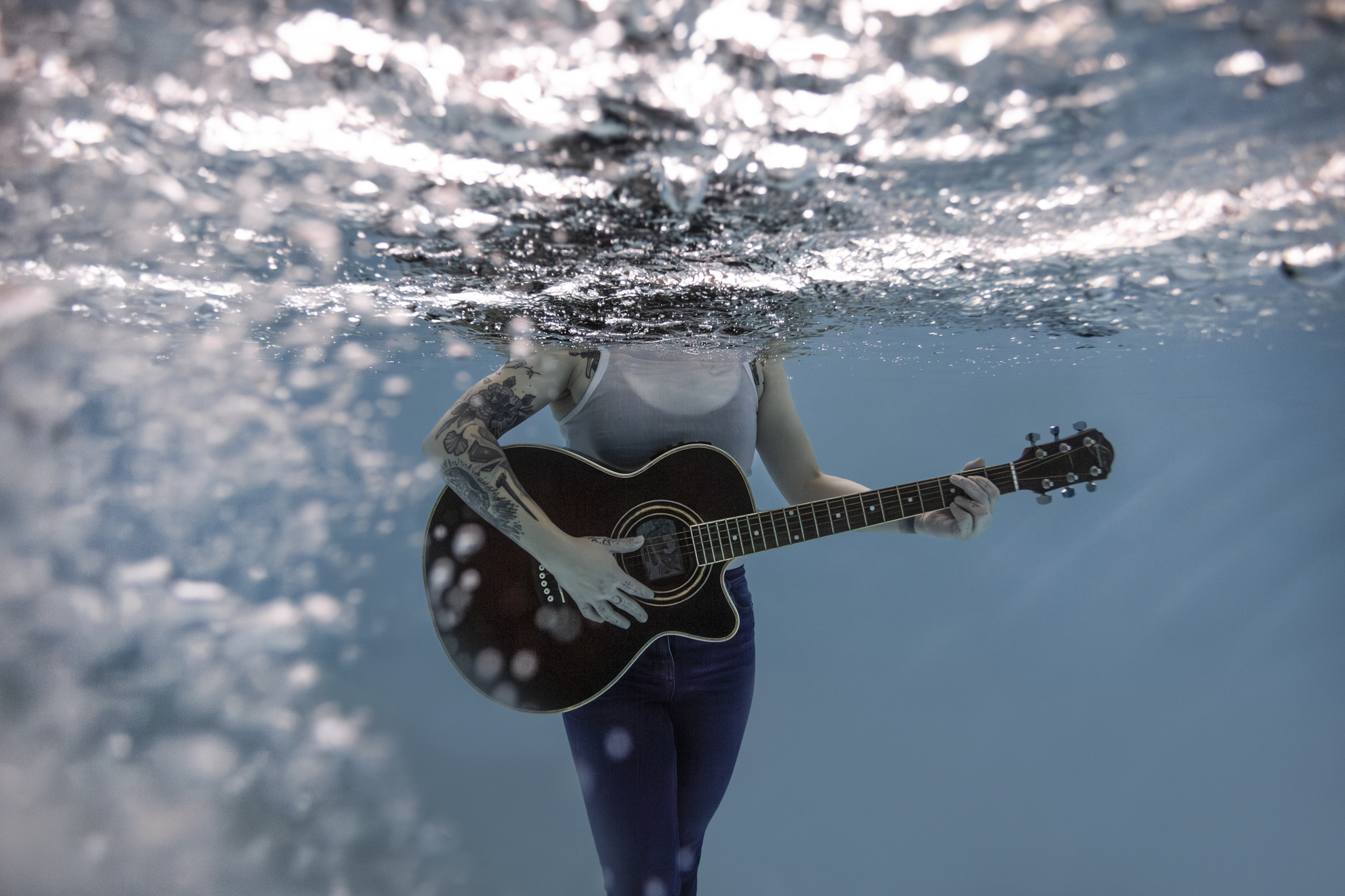 Femme en immersion sous l’eau tenant une guitare pendant une séance photo aquatique artistique