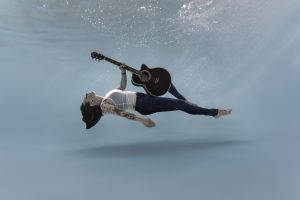 Femme immergée sous l’eau tenant une guitare, création artistique en photographie aquatique à Nantes